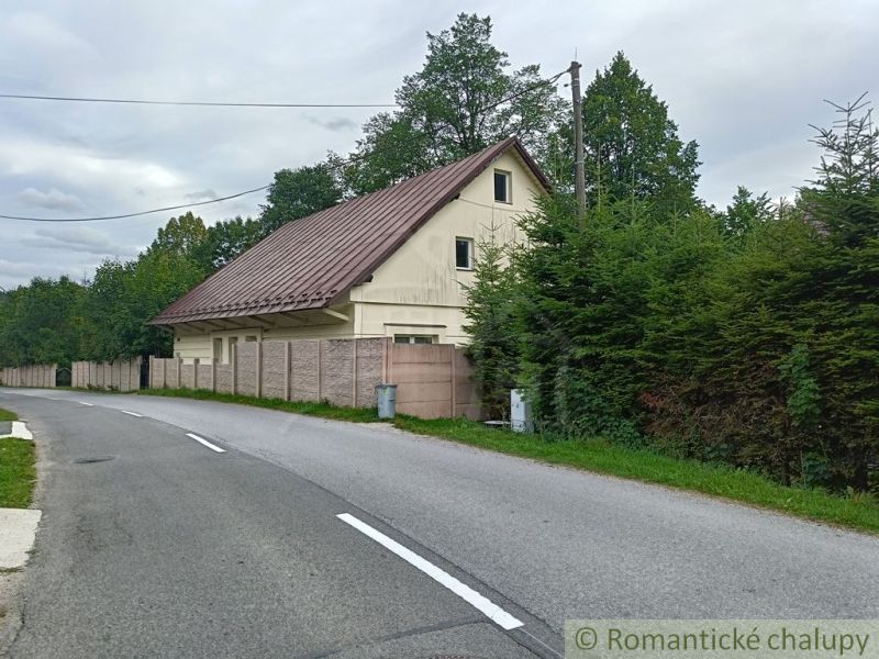 Családi ház Staskovban bádogtetővel, fákkal és kerítéssel körülvéve.