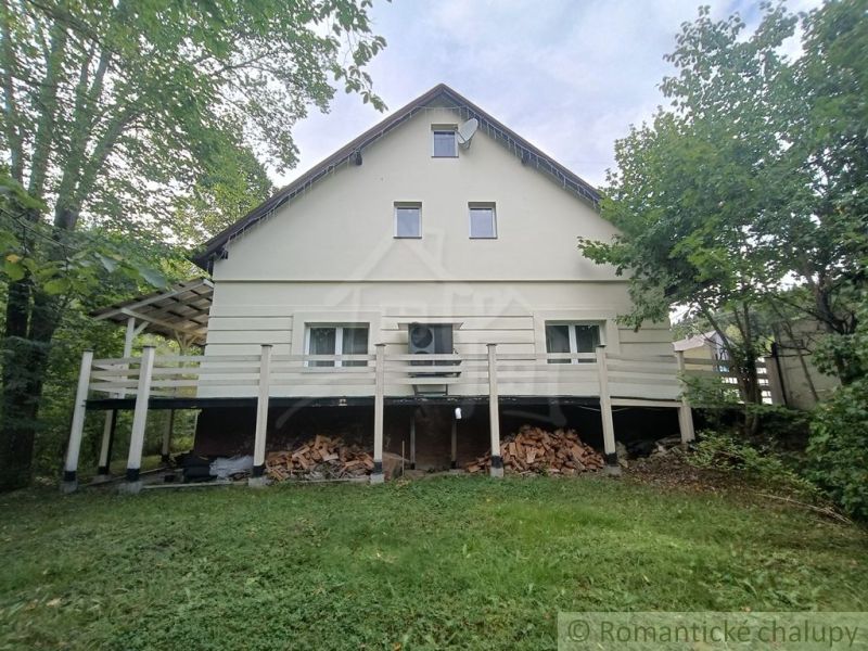 Családi ház Staškovóban, zölddel körülvéve, a terasz alatt tárolt fával.