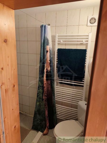 Fürdőszoba a házikóban csempézett fallal, függönnyel és fűtőtesttel.