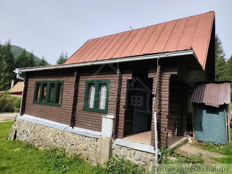 Fából készült házikó bádogtetővel a Rajecká Lesná természetében, zölddel körülvéve.