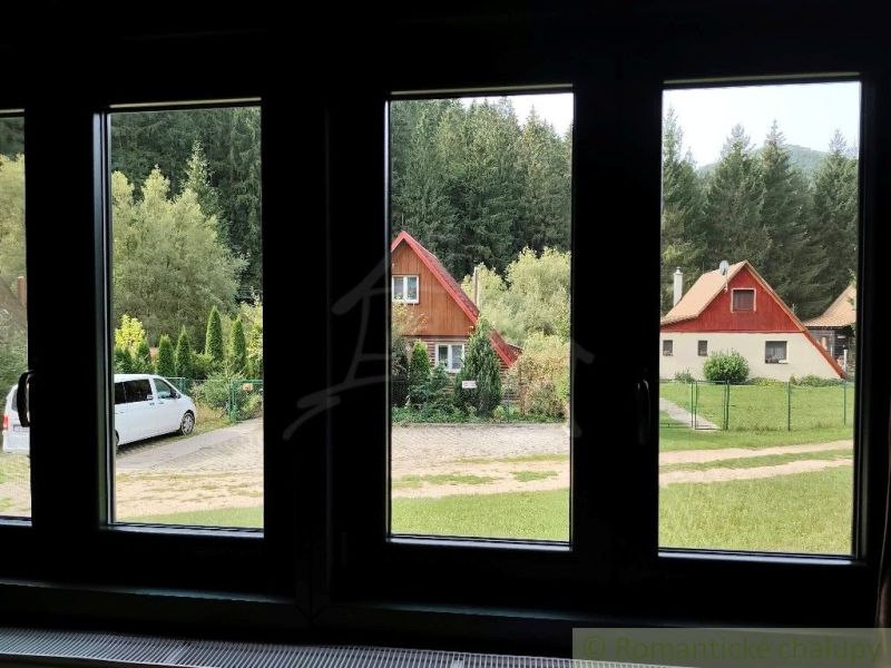 Kilátás a Rajecká Lesná-i házakra, amelyeket zöld növényzet és autók vesznek körül.