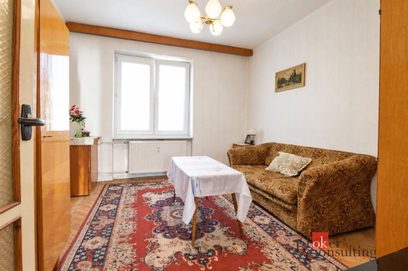 Nappali egy kétszobás lakásban, szőnyeggel és kanapéval, fa dekoros padlóval.