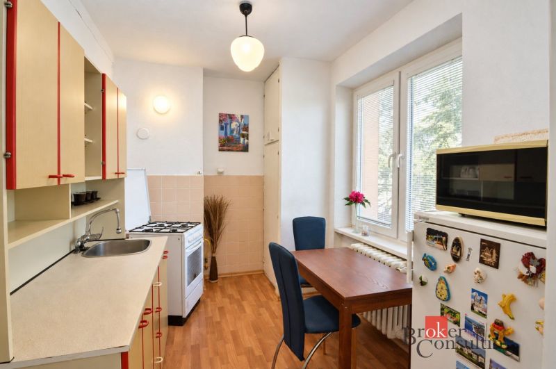 Konyha egy kétszobás lakásban fa dekor padlóval, étkezőasztallal és modern felszereléssel.