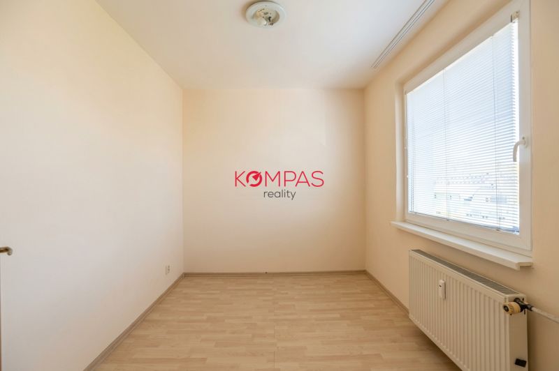 Szoba egy háromszobás lakásban fa dekorációjú padlóval és nagy ablakkal.
