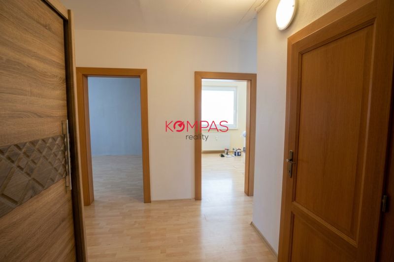 Folyosó egy 3 szobás lakásban fa mintázatú padlóval és világos ajtókkal.