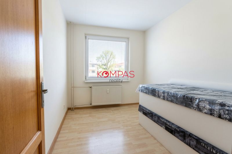 Világos szoba egy háromszobás lakásban, fa dekorációs padlóval és ággyal.