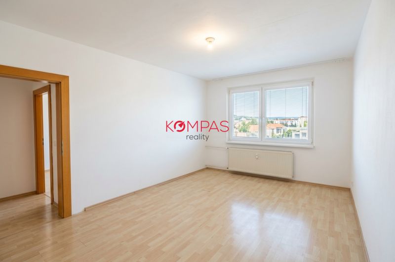 Szoba egy háromszobás lakásban nagy ablakkal és fa dekorációjú padlóval.