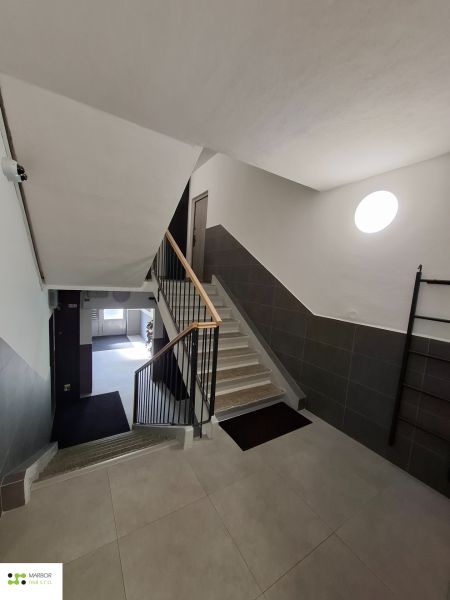 A társasház lépcsőháza egy 3 szobás lakásban modern csempékkel és korláttal.