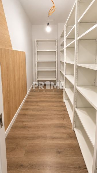 Tároló fehér polcokkal és fa dekoros padlóval egy kétszobás lakásban.