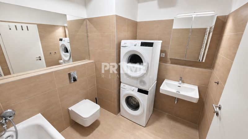 A fürdőszoba egy kétszobás lakásban zuhanyzóval, mosdóval, WC-vel és mosógéppel szárítóval.