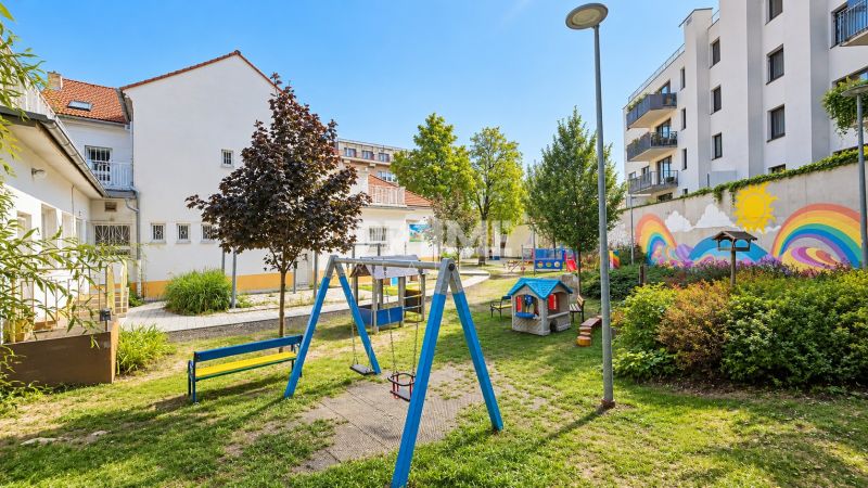 Játszótér épületekkel körülvéve, színes falfestményekkel a Sancova utcán.
