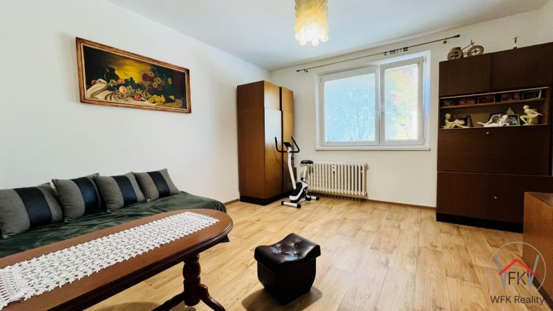 Szoba egy háromszobás lakásban, fa dekoros padlóval, vintage bútorokkal és egy képpel a falon.