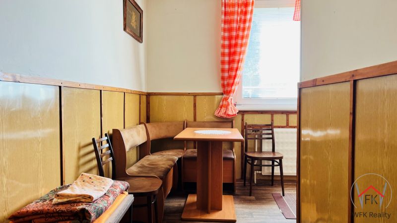 Konyhasarok egy 3 szobás lakásban fa dekorációval és ülőhellyel, asztallal.