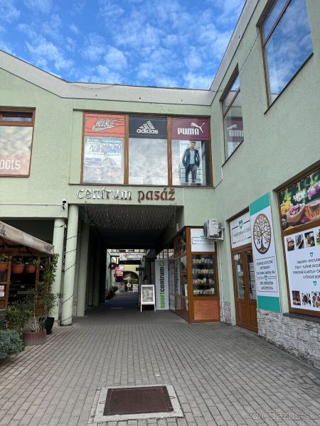 Üzlethelyiségek Nagytapolcsányban, a központi átjáró bejáratával és kirakatokra néző kilátással.
