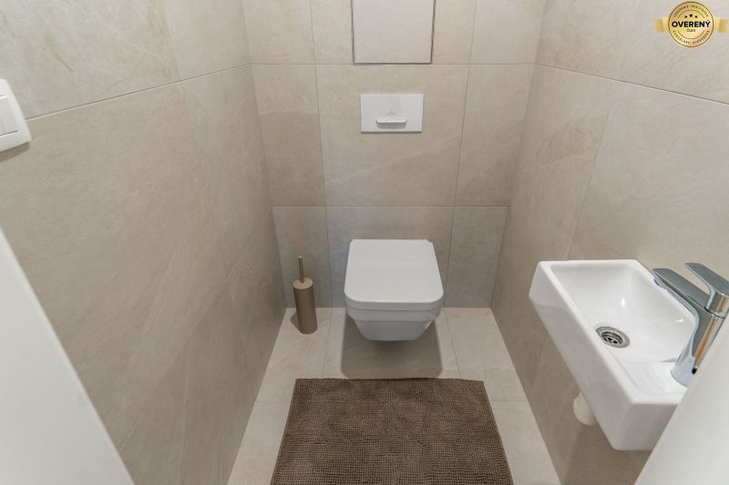 Függesztett WC-vel, kis mosdóval és bézs csempével ellátott WC, Lakásépítés.