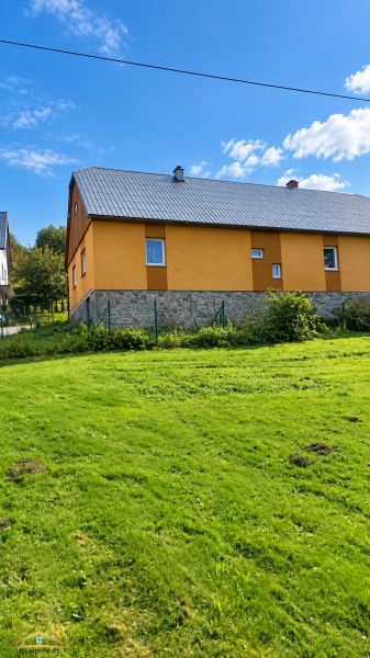 Családi ház Oščadnicában, a Košariská utcában, sárga homlokzattal és füvesített telekkel.