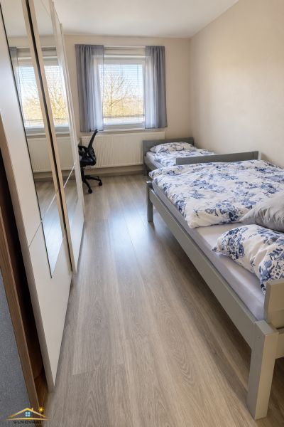Kétágyas szoba fa mintás padlóval egy családi házban.