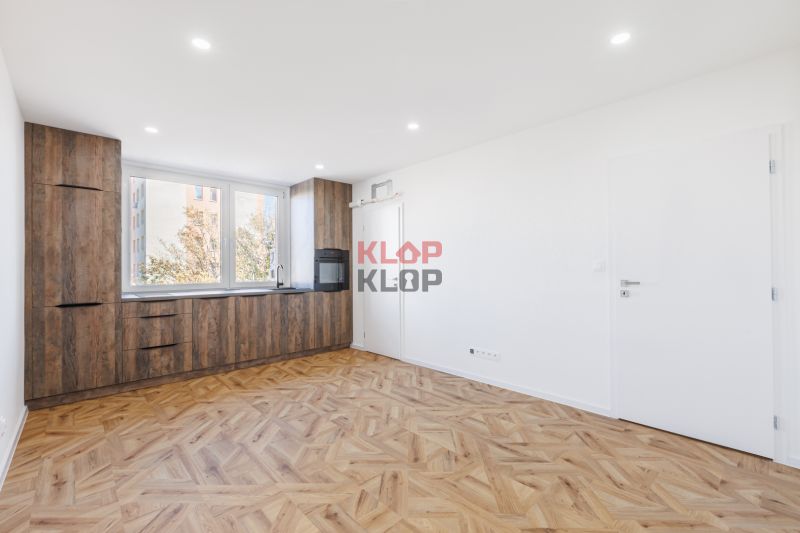 Nappali egy két szobás lakásban konyhabútorral és fa dekorációjú padlóval.