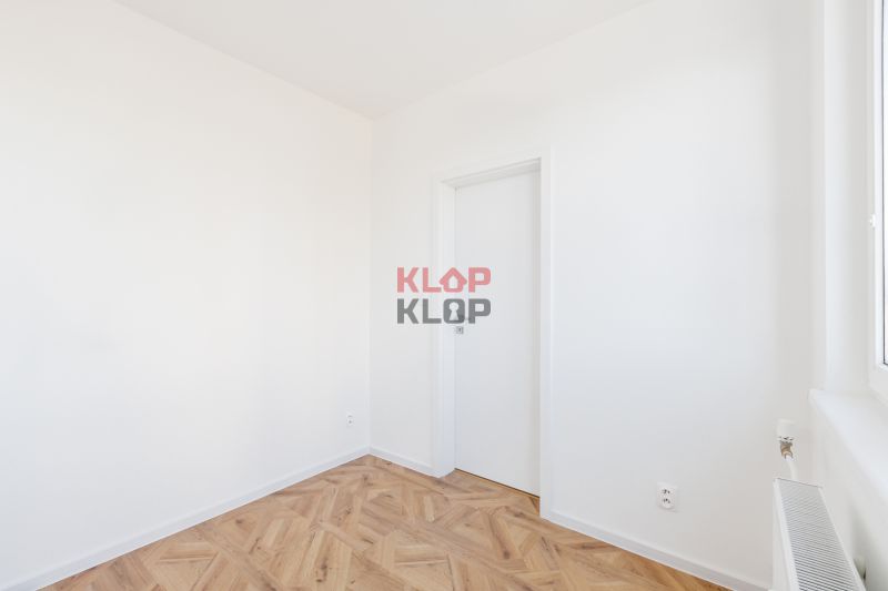 Szoba fehér falakkal és fa mintázatú padlóval, 2 szobás lakás.