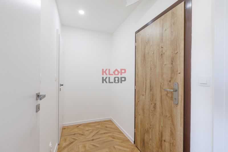 2 szobás lakás előszobája fa mintázatú padlóval és fa ajtókkal.