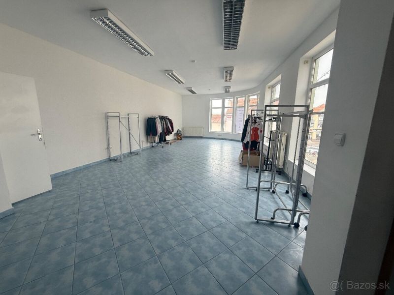 Kereskedelmi helyiségek kék csempével és ruhatartó állványokkal.