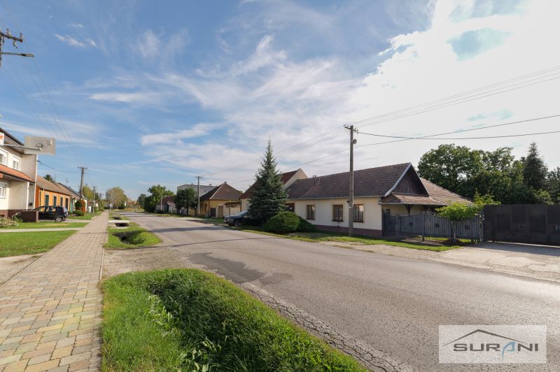 Családi házak a Štefanová-i Fő utcán, rendezett kerttel és tiszta égbolttal.