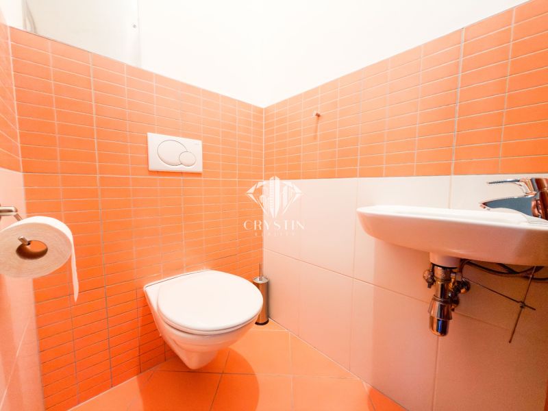 Fürdőszoba egy háromszobás lakásban narancssárga csempékkel és függesztett WC-vel.