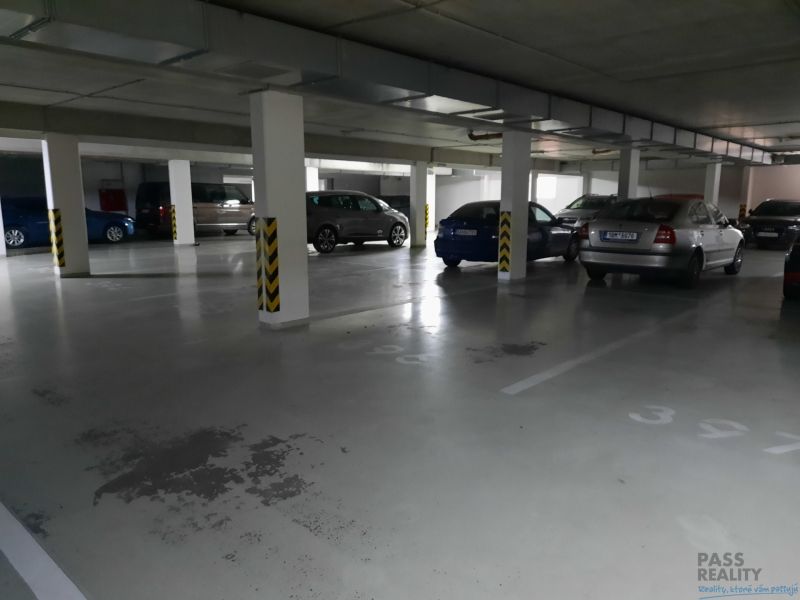 Podzemné garážové státie s parkovanými autami v 2-izbovom byte.