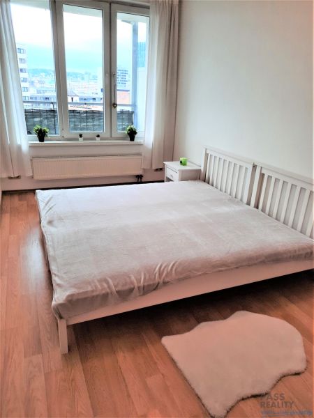 Világos hálószoba egy kétszobás lakásban ablakkal és fa dekorációjú padlóval.
