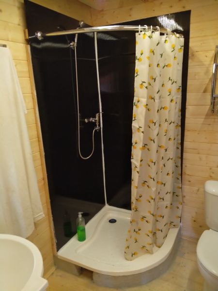 Zuhanykabin a házon virágos függönnyel és fa mintázatú padlóval.