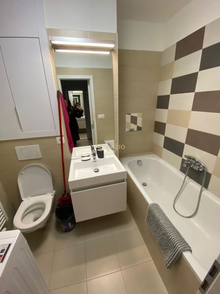 Fürdőszoba egy kétszobás lakásban káddal, mosdóval és WC-vel, csempézett fal.
