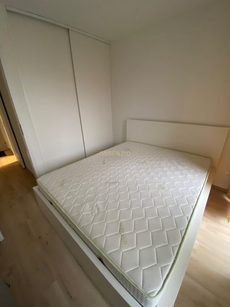 Hálószoba egy kétszobás lakásban nagy ággyal és beépített szekrénnyel.