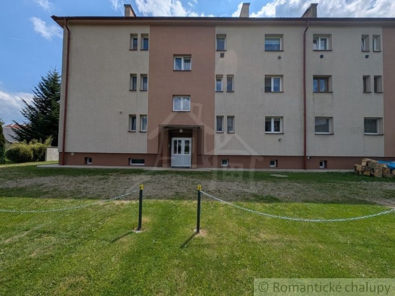 Háromemeletes lakóház Medzilaborceban zöld udvarral, világos homlokzatokkal.