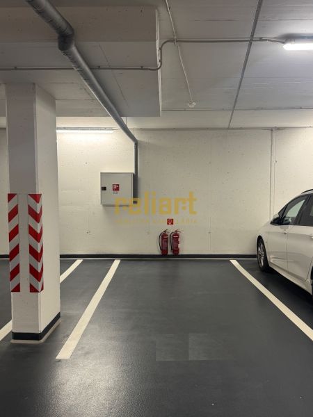 Földalatti parkolóhely jól látható jelzéssel és mellette egy fehér autó.
