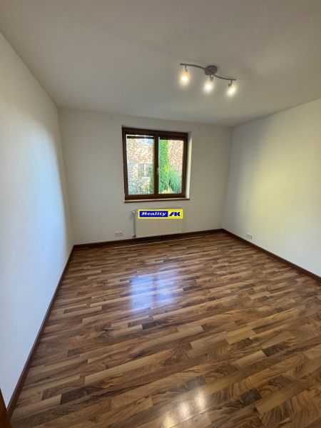 Szoba egy családi házban, fa dekoros padlóval és egyszerű világítással.