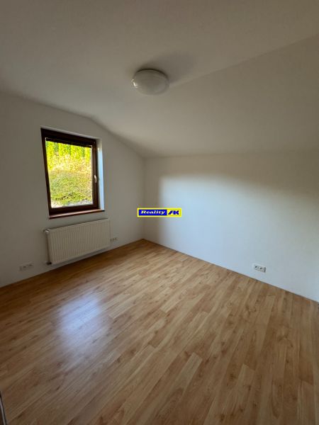 Szoba egy családi házban, fa dekorációjú padlóval és radiátorral az ablak alatt.