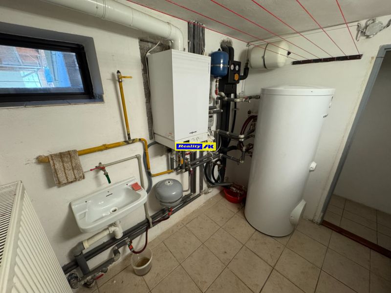 Technikai helyiség radiátorral, mosdóval és bojlerrel egy családi házban.