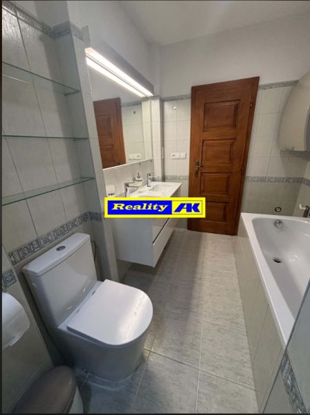 Fürdőszoba káddal és WC-vel egy családi házban, fehér csempékkel és faajtókkal.