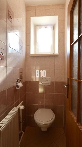 Kis fürdőszoba ablakkal, csempékkel és WC-vel egy családi házban.