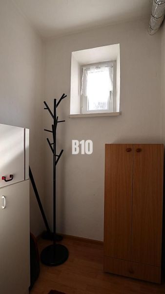 Kis szoba egy családi házban fogassal és szekrénnyel, fa dekorációjú padlóval.