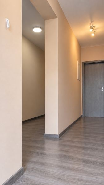 Folyosó egy családi házban, fa dekorációjú padlóval és semleges falakkal.