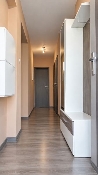 Folyosó egy családi házban fa mintázatú padlóval és világos falakkal.