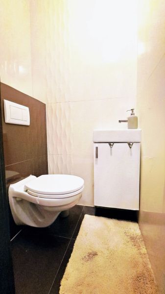 Fürdőszoba családi házban WC-vel, mosdóval és dombornyomott csempékkel.