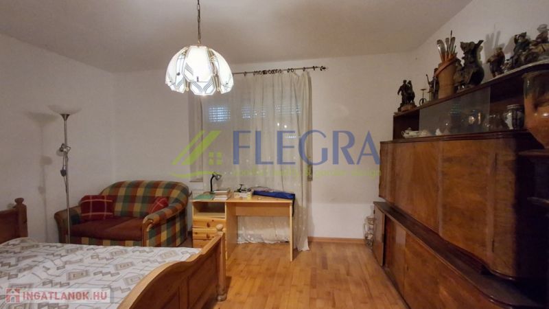 Szoba egy családi házban egy ággyal és fa dekorációjú padlóval.