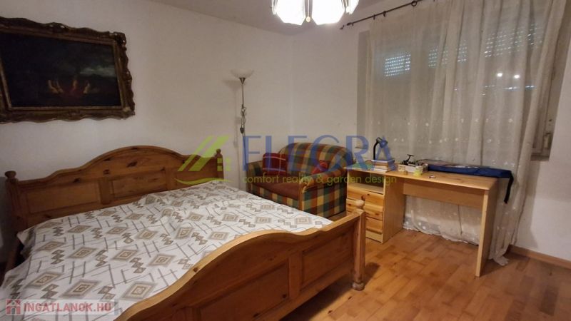 Hálószoba egy családi házban fa dekorációval, ággyal és íróasztallal.