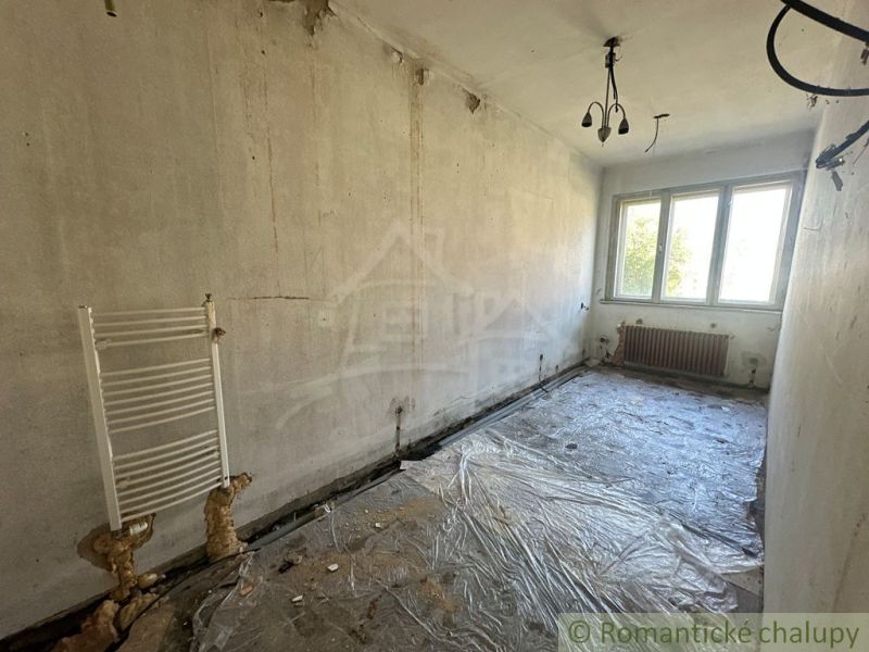 Üres szoba műanyag ablakkal és fedetlen radiátorokkal egy családi házban.